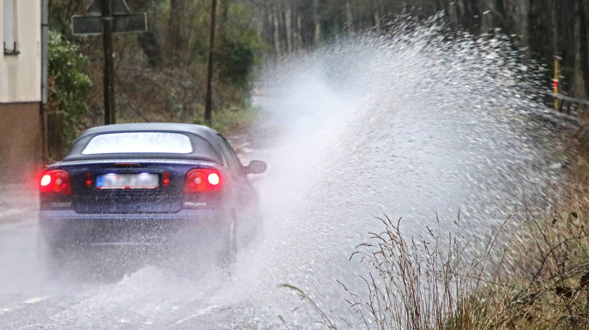 Starkregen auf einer Straße: Im ganzen Osten sowie in der Region München wird am Montag vor heftigen Regenfällen gewarnt.