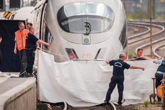 Frankfurt/Main: Polizisten und Feuerwehrleute spannen im Hauptbahnhof eine weiße Plane als Sichtschutz vor einen ICE.