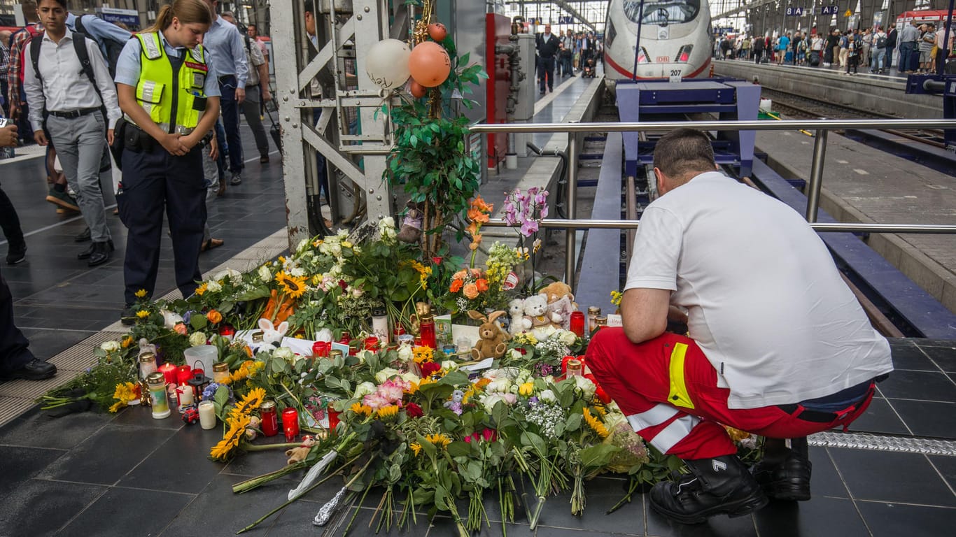 Ein Ersthelfer legt am Bahnsteig 7 im Frankfurter Hauptbahnhof Blumen nieder: Ein achtjähriger Junge wurde am Dienstag vor einen einfahrenden ICE gestoßen und starb.