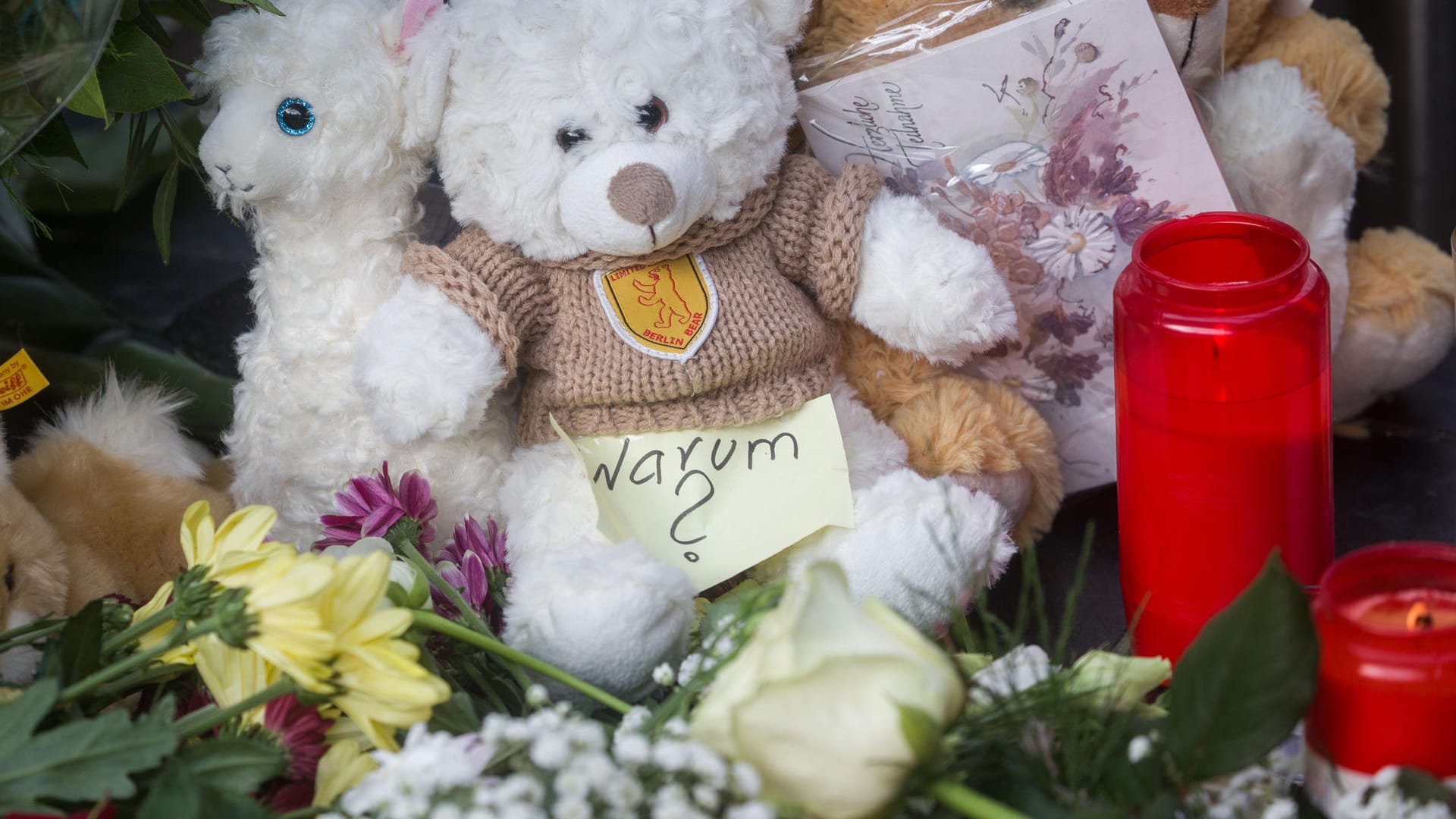 Ein Zettel mit der Aufschrift "Warum?" liegt neben Plüschtieren, Blumen und Kerzen am Frankfurter Hauptbahnhof.