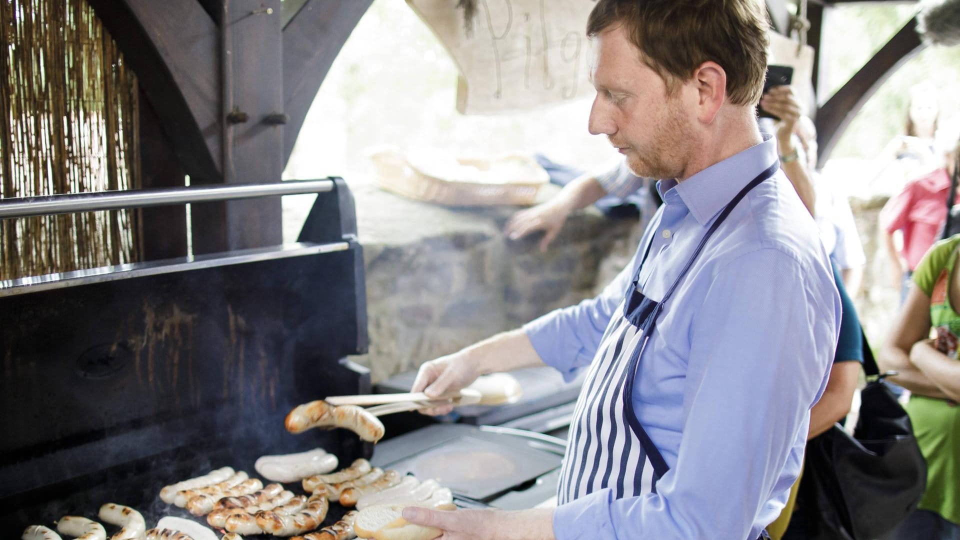 Sachsens Ministerpräsident Michael Kretschmer grillt auf seiner Sommertour Bratwürste.