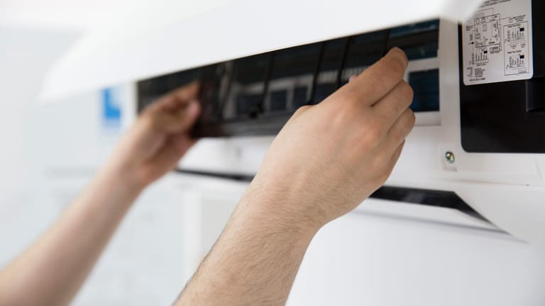 Gitter wird aus der Klimaanlage genommen: Eine regelmäßige Reinigung verhindert, dass über die Klimaanlage Viren in der Wohnung verbreitet werden.