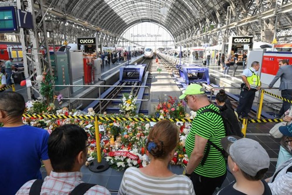 Passanten stehen am Gleis 7 des Frankfurter Hauptbahnhofs vor einem Meer aus Blumen und Kuscheltieren.
