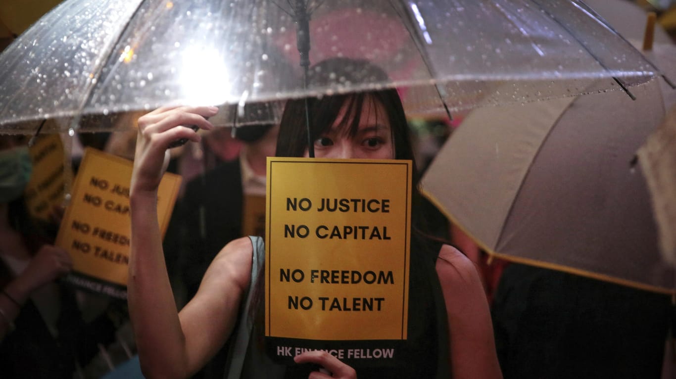 Hongkong: Eine Frau mit Regenschirm hält während einer Demonstration im Chater Garden ein Schild mit der Aufschrift «No Justice No Capital No Freedom No Talent» in der Hand.