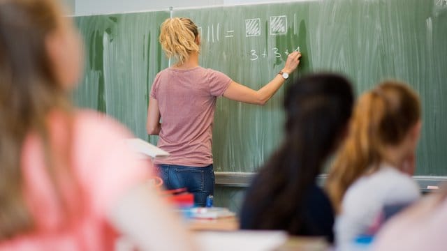 Eine Lehrerin schreibt an eine Schultafel im Mathematikunterricht einer achten Klasse an einer Integrierten Gesamtschule.