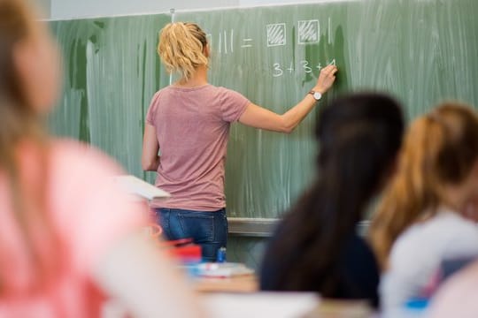 Eine Lehrerin schreibt an eine Schultafel im Mathematikunterricht einer achten Klasse an einer Integrierten Gesamtschule.