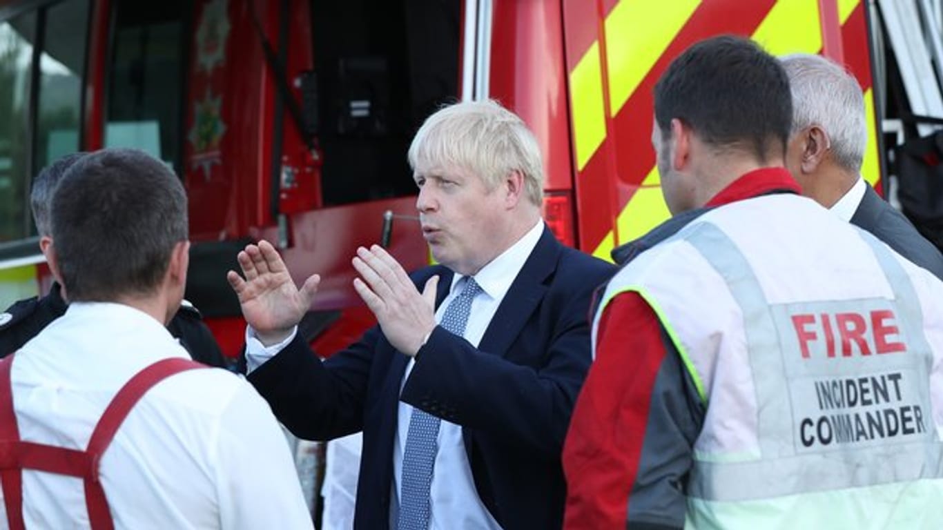 Der britische Premierminister Boris Johnson spricht während seines Besuchs in Whaley Bridge mit Einsatzkräften.