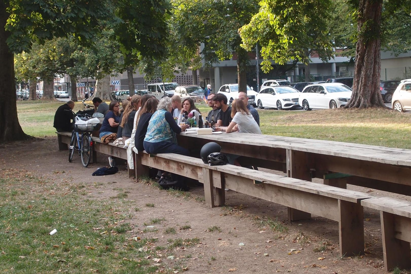 Kölner sitzen am "Langen Tisch": Der Holztisch ist rund 30 Meter lang und ein beliebter Treffpunkt. Sein Erhalt ist allerdings nicht sicher.