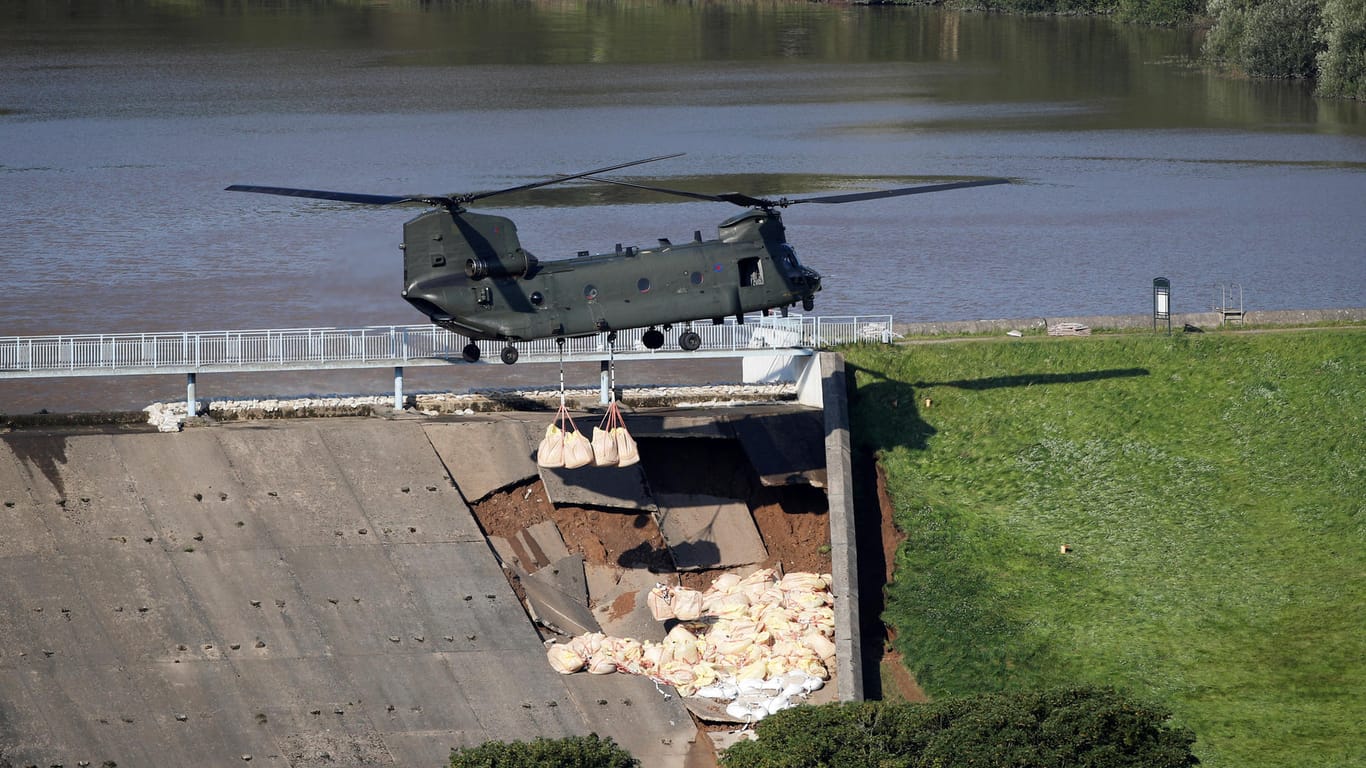 Der Transport-Helikopter vom Typ "Chinook" wirft Sandsäcke an dem beschädigten Staudamm ab: Sand, Kies und Schotter sollen das Wasser aufhalten.