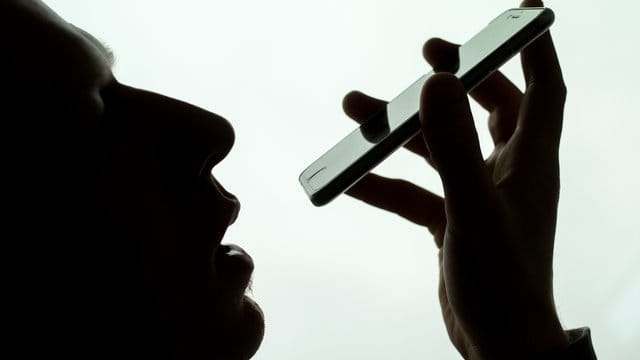 Ein Mann spricht in sein iPhone. Ein Mann spricht in sein iPhone.