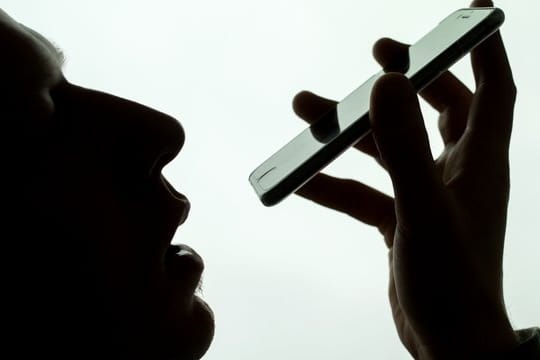 Ein Mann spricht in sein iPhone.