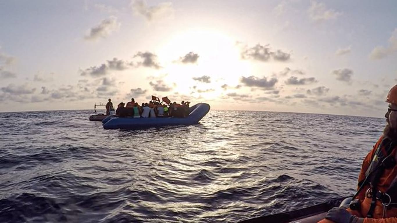 Das von der Seenotrettungsorganisation Sea-Eye herausgegebene Foto vom Mittwoch zeigt Seenotretter der "Alan Kurdi" vor einem Schlauchboot voller Flüchtlinge.