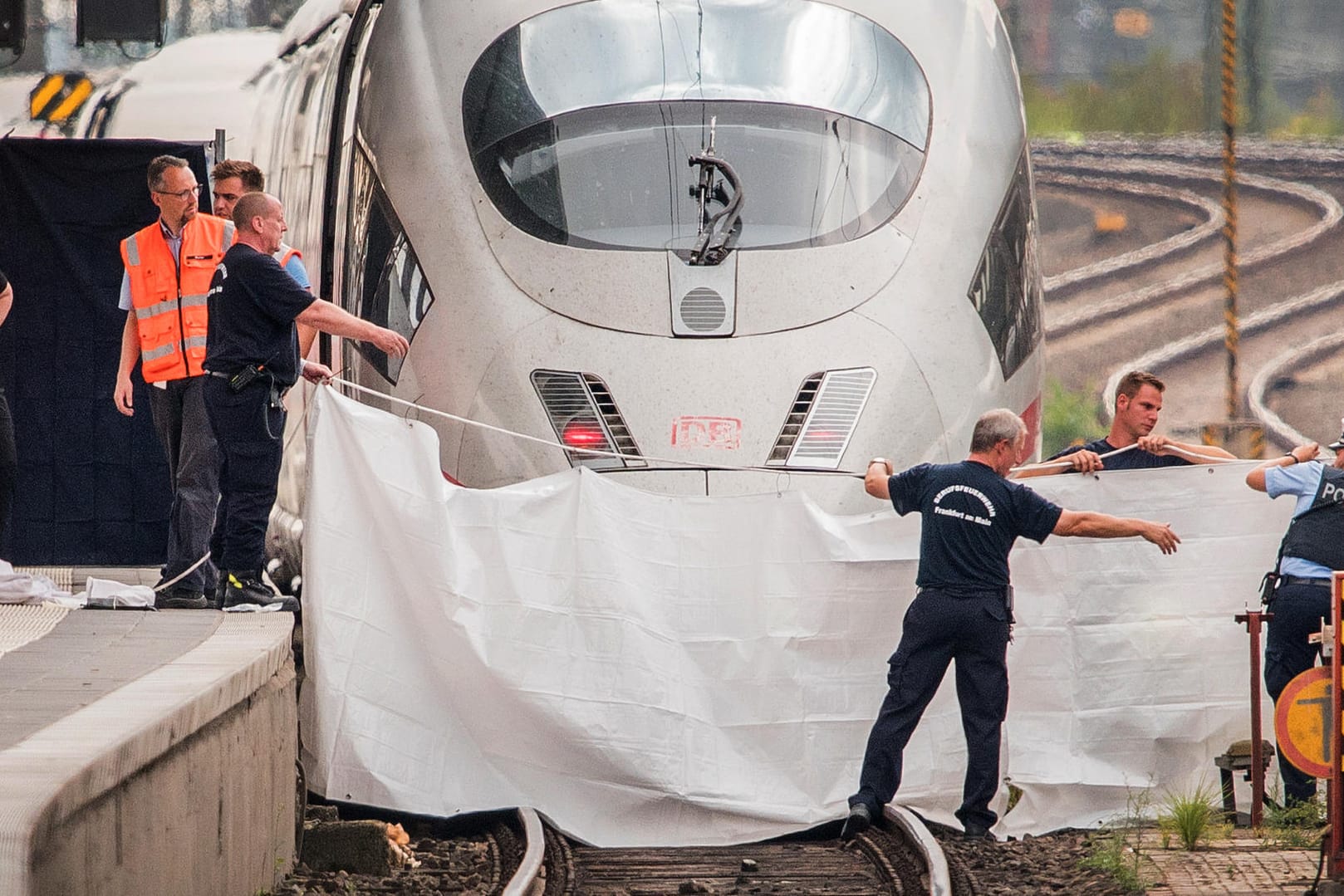 Frankfurt: Polizisten und Feuerwehrleute spannen im Hauptbahnhof eine weiße Plane als Sichtschutz vor einen ICE. Ein achtjähriger Junge ist im Frankfurter Hauptbahnhof von einem Mann vor den einfahrenden ICE gestoßen und getötet worden.