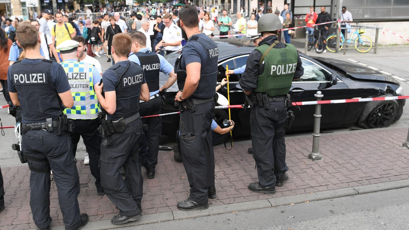 Polizeibeamte stehen am Frankfurter Hauptbahnhof an einem schwarzen BMW, mit dem mehrere Täter nach einem Raubüberfall geflüchtet waren.