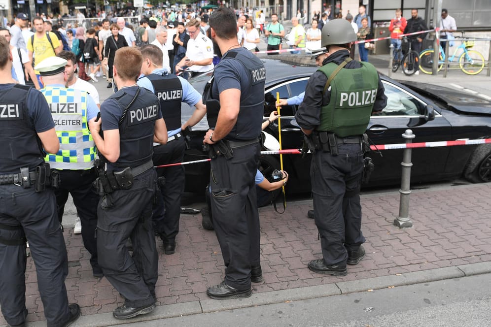 Polizeibeamte stehen am Frankfurter Hauptbahnhof an einem schwarzen BMW, mit dem mehrere Täter nach einem Raubüberfall geflüchtet waren.
