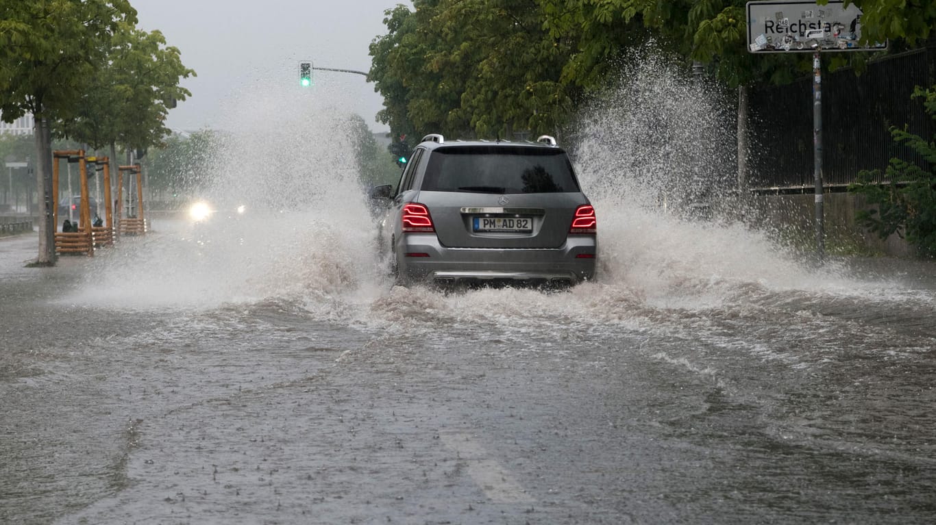 Auto fährt durch überflutete Straße: In Berlin mussten die Freiwilligen Feuerwehren in den Dienst gerufen werden.