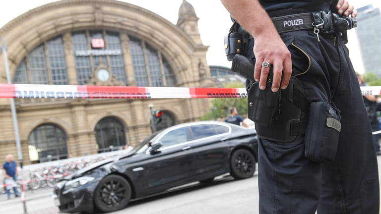 Großeinsatz am Frankfurter Hauptbahnhof: Ein Polizist bewacht den schwarzen BMW, mit dem mehrere Täter geflüchtet waren.