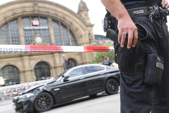 Großeinsatz am Frankfurter Hauptbahnhof: Ein Polizist bewacht den schwarzen BMW, mit dem mehrere Täter geflüchtet waren.