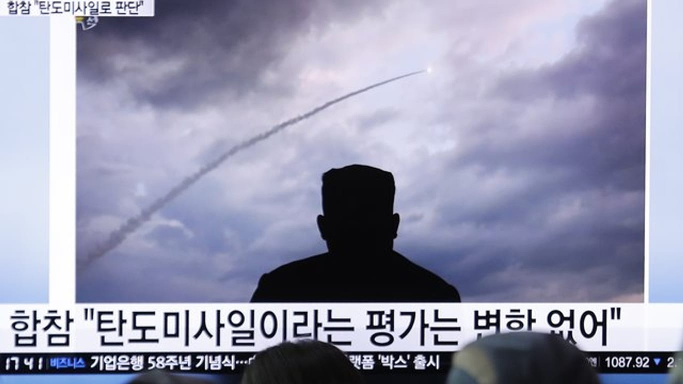 Passanten verfolgen an einem Bahnhof auf einem Fernseher eine Nachrichtensendung über einen Raketentest von Nordkorea.