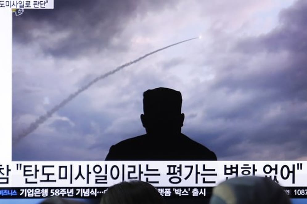 Passanten verfolgen an einem Bahnhof auf einem Fernseher eine Nachrichtensendung über einen Raketentest von Nordkorea.