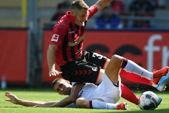 Cagliaris Federico Mattiello (u) trennt Freiburgs Christian Günther per Grätsche vom Ball.