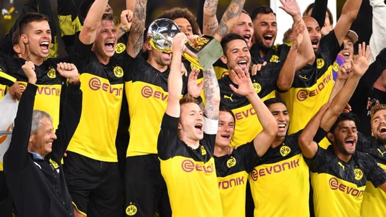 Dortmunds Marco Reus (M) bejubelt mit seinem Trainer Lucien Favre (l) und Mitspielern den Gewinn des Supercups 2019.