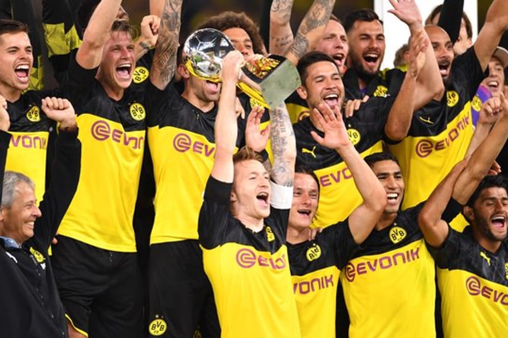 Dortmunds Marco Reus (M) bejubelt mit seinem Trainer Lucien Favre (l) und Mitspielern den Gewinn des Supercups 2019.