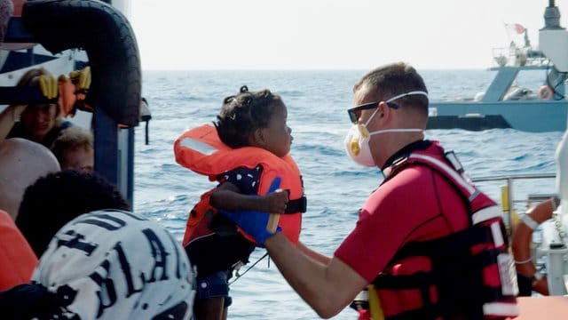 Ein Kind wird vom Seenotrettungsschiff "Alan Kurdi" auf ein Schiff der maltesischen Armee gehoben. Ein Kind wird vom Seenotrettungsschiff "Alan Kurdi" auf ein Schiff der maltesischen Armee gehoben.