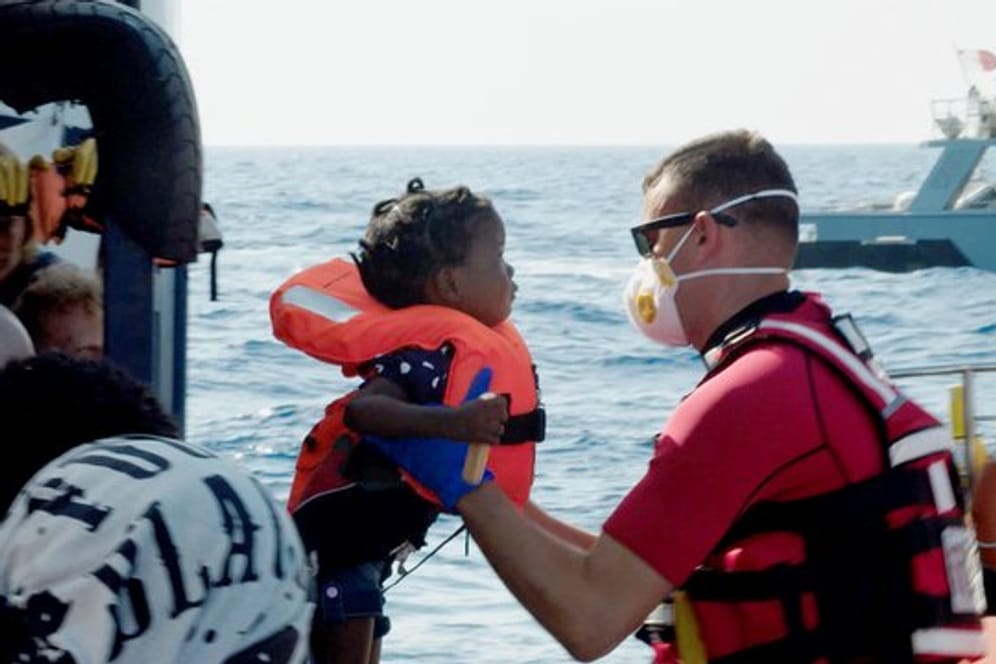 Ein Kind wird vom Seenotrettungsschiff "Alan Kurdi" auf ein Schiff der maltesischen Armee gehoben.