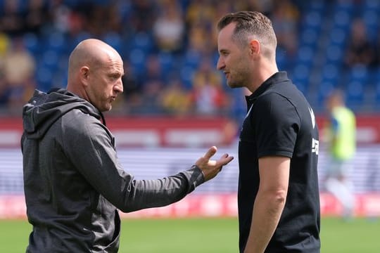 Duisburgs Trainer Torsten Lieberknecht (l) und Braunschweigs Christian Flüthmann unterhalten sich vor dem Spiel.