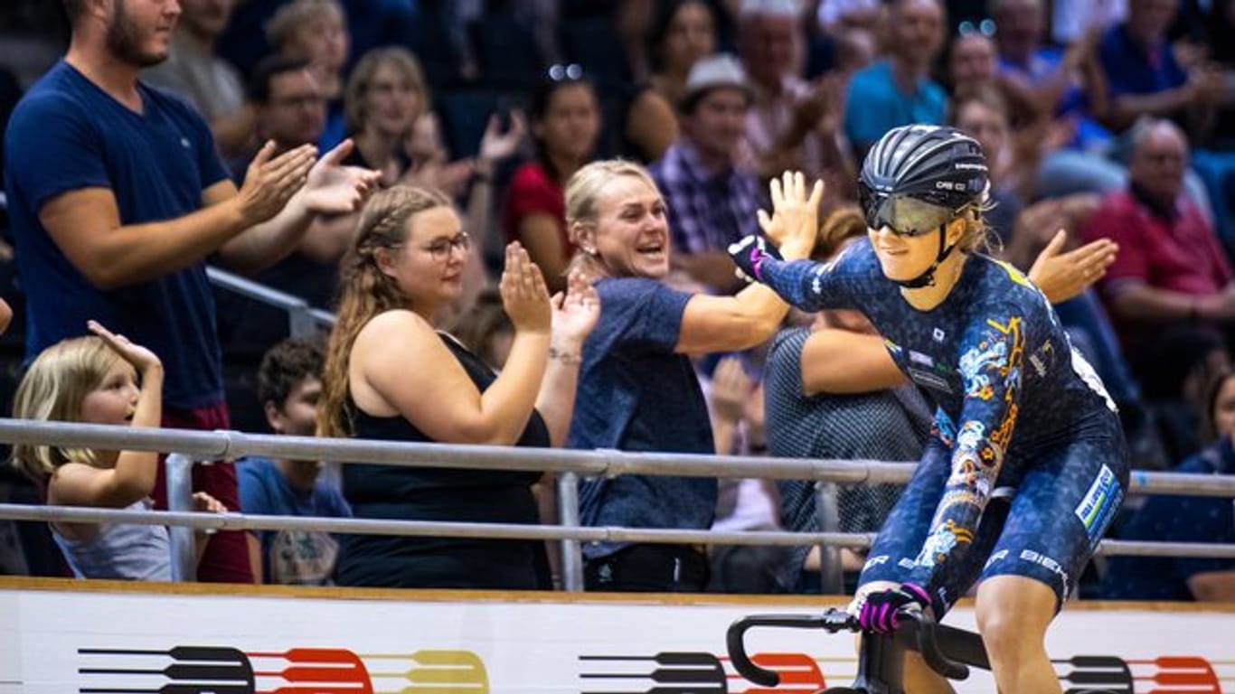 Bahnradfahrerin Lea Sophie Friedrich jubelt mit Zuschauern über ihren Sieg.