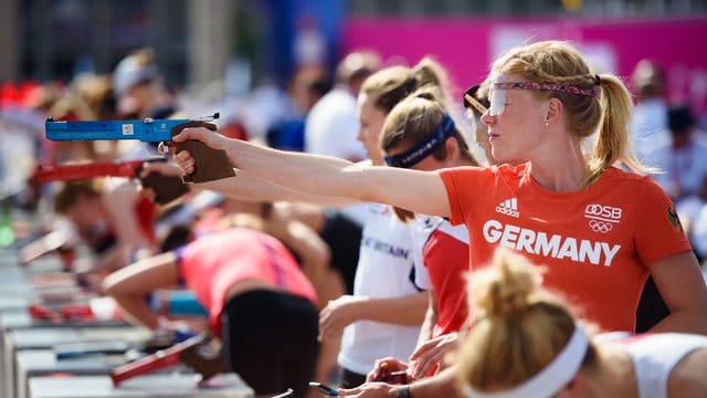 Annika Schleu zielt während der Aufwärmphase mit ihrer Laser-Pistole in der Hand auf eine Zielscheibe.