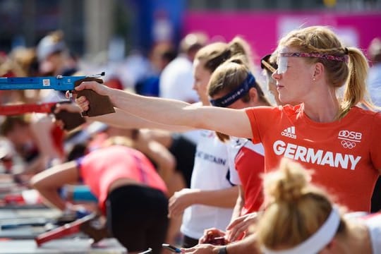 Annika Schleu zielt während der Aufwärmphase mit ihrer Laser-Pistole in der Hand auf eine Zielscheibe.