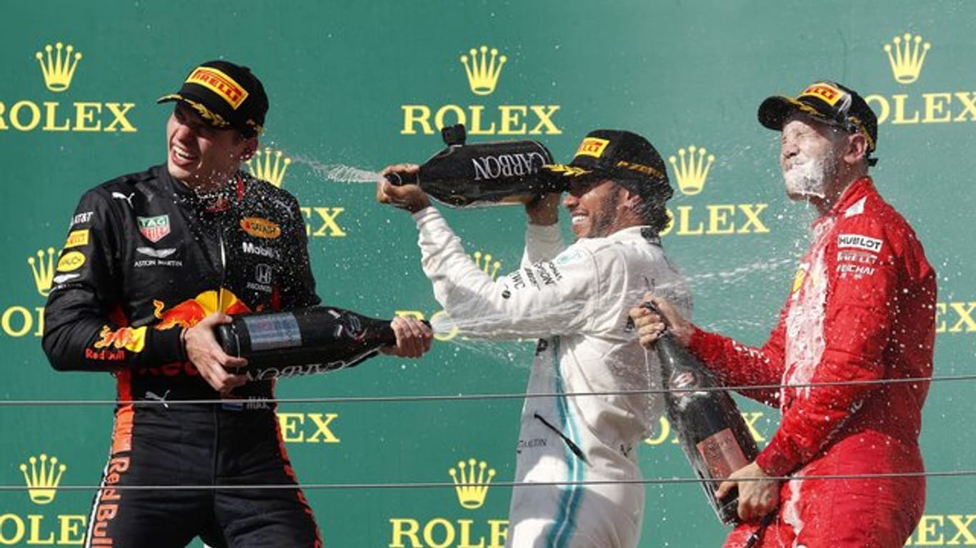 Champagnerdusche: Sieger Lewis Hamilton (M) mit Max Verstappen (l) und Sebastian Vettel auf dem Podium in Budapest.