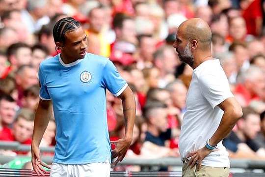 Manchester Citys Leroy Sané (l) spricht nach seiner Auswechslung mit Trainer Pep Guardiola.