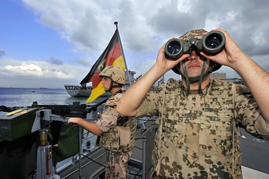 Deutsche Marine-Soldaten halten an Bord der Fregatte "Karlsruhe" an einem Maschinengewehr Wache.