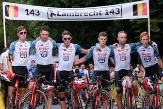 Die Fahrer des Teams Lotto Soudal stehen für eine Schweigeminute zum Tod von Bjorg Lambrecht mit Trauerflor vor einem Banner.