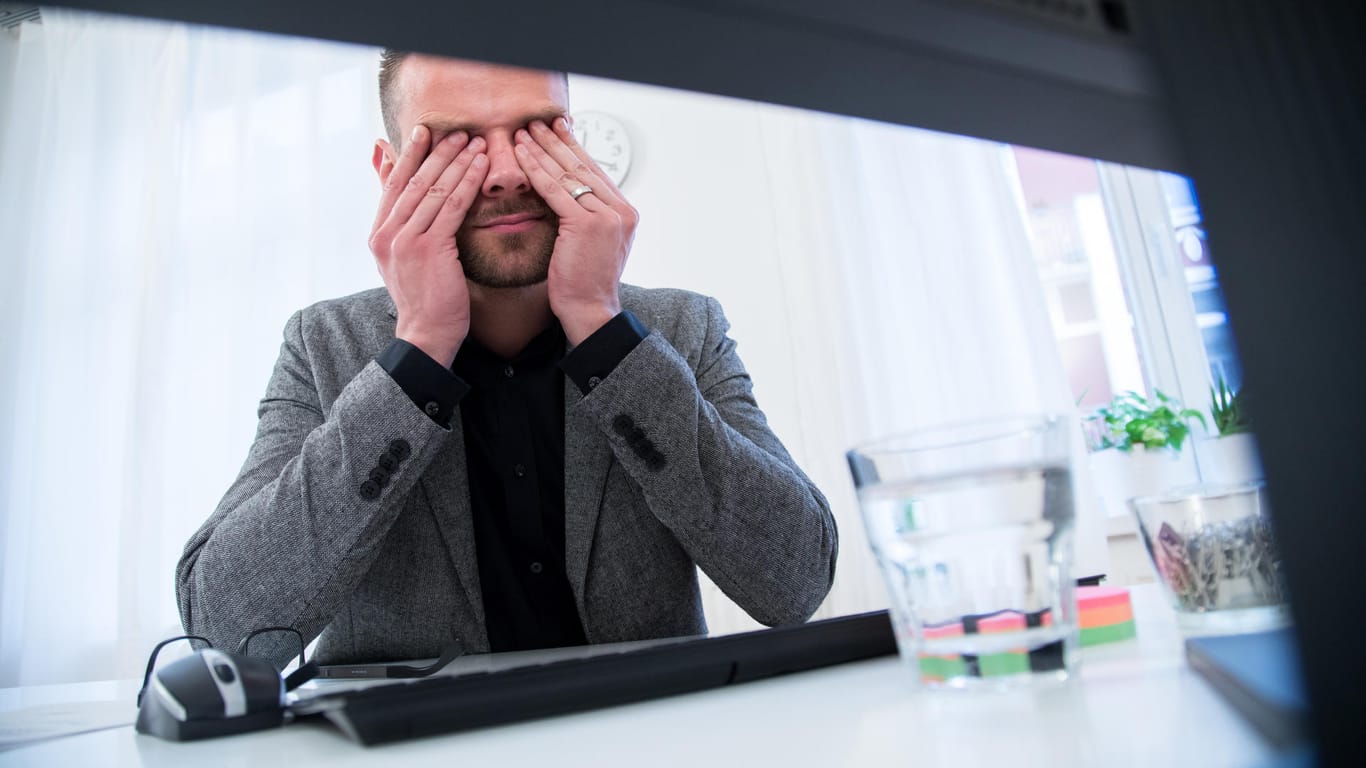 Ein Mann reibt sich die Augen: Gegen müde Augen bei der Arbeit hilft es, den richtigen Abstand zum Bildschirm einzuhalten und regelmäßig Pausen zu machen.