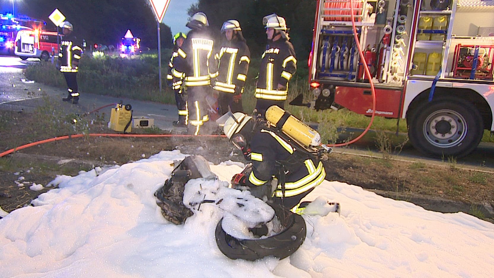 Ein Feuerwehrmann kniet neben dem ausgebrannten Motorrad: Auf dem Motorrad saßen eine 23-jährige Frau und ein 25-jähriger Mann, sie starben bei dem Unfall.