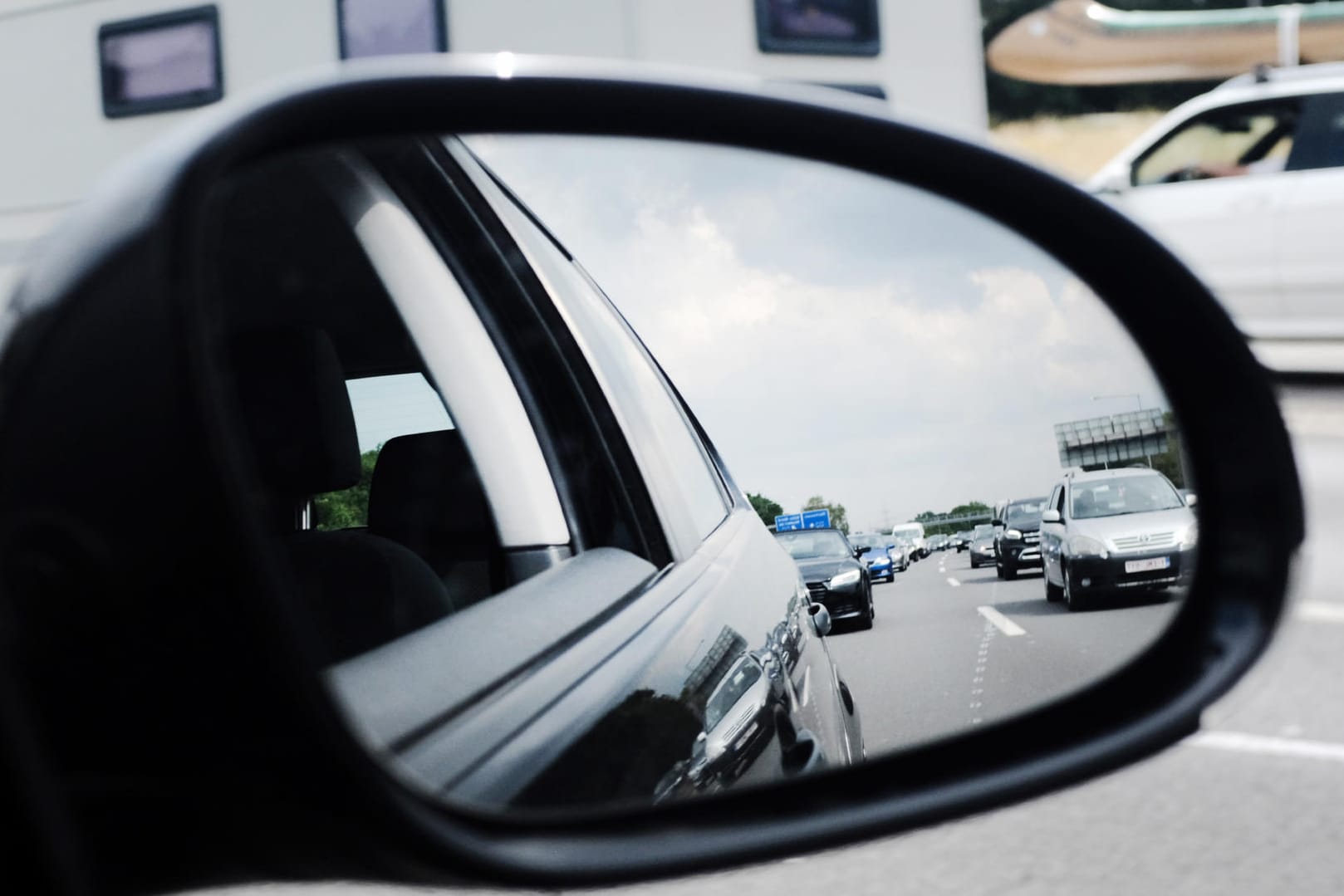 Im Außenspiegel eines Autos ist ein Stau auf einer Autobahn zu sehen: Die Autoclubs rechnen am kommenden Wochenende mit vollen Straßen.