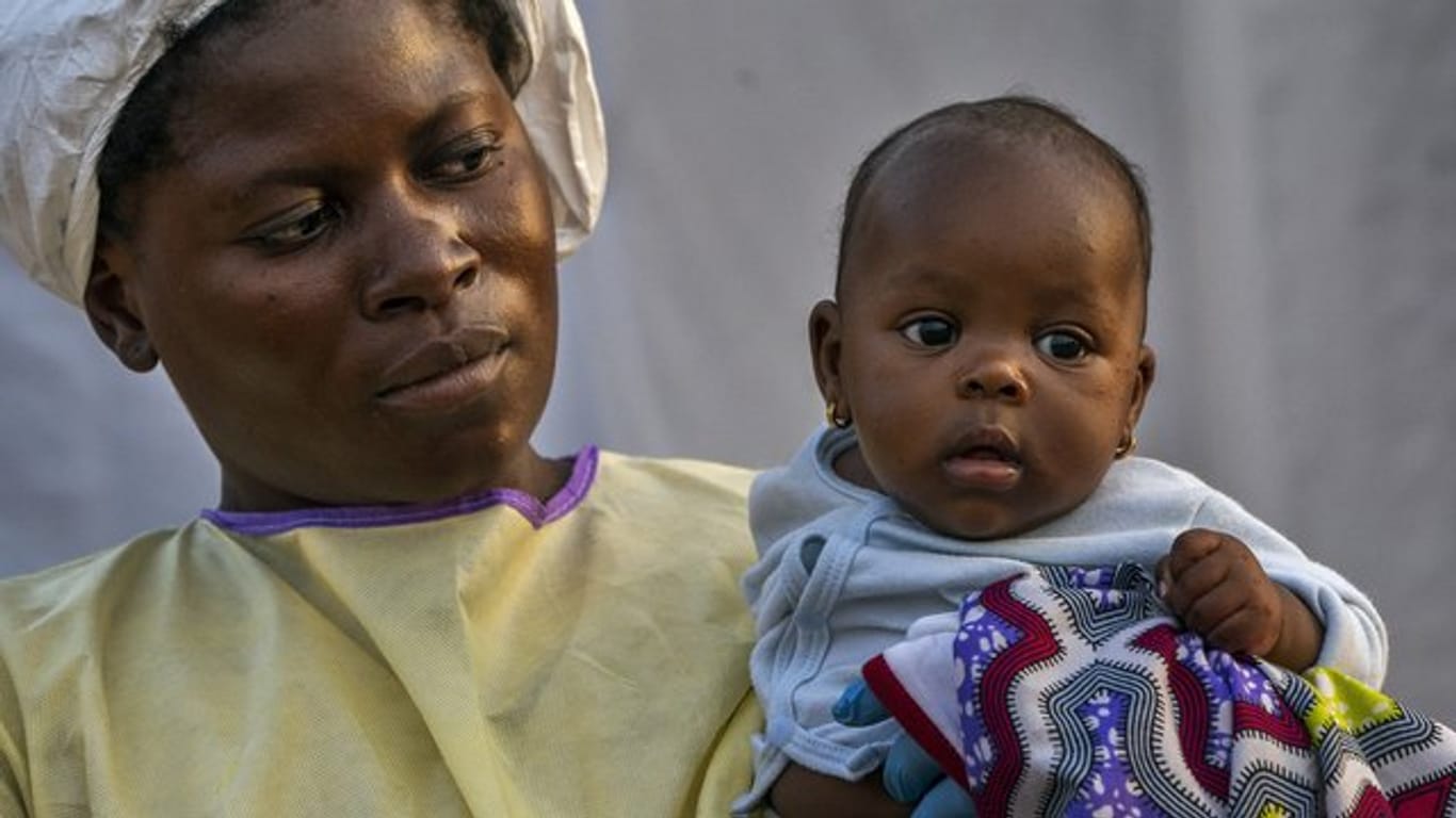 Eine Krankenschwester trägt nach einem Ebolatest in einem Ebola-Behandlungszentrum die wenige Monate alte Lahya Kathembo auf dem Arm.