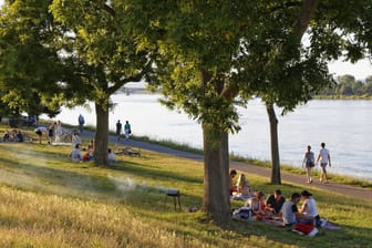 Leute beim Grillen an einem Sommerabend am Rheinufer in Mainz: Zeit, die letzten Sonnenstrahlen zu genießen.