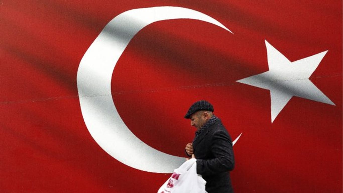 Ein Mann geht an einer türkischen Flagge vorbei.