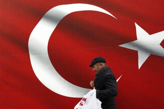 Ein Mann geht an einer türkischen Flagge vorbei.