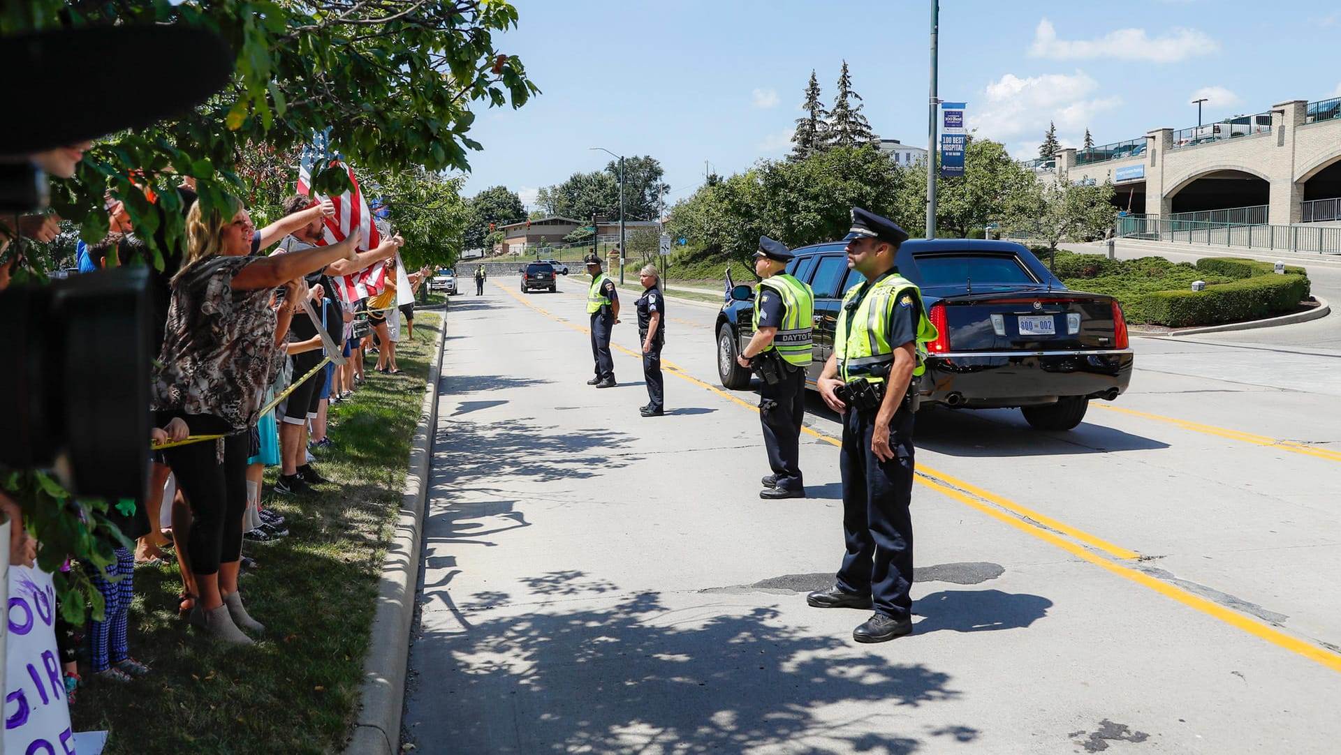 Proteste vor dem Miami Valley Hospital in Dayton: Links Demonstranten, rechts die Präsidenten-Limousine, dazwischen Polizisten.