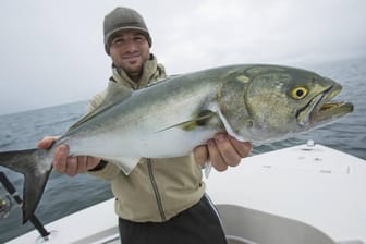 Ein Mann hält einen Blaufisch: An der Costa Blanca ist eine Frau beim Schwimmen verletzt worden. (Archivbild)