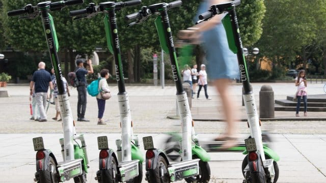 Eine Frau fährt auf vor auf einem E-Scooter des Anbieters Lime.