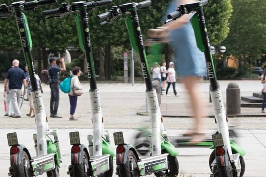 Eine Frau fährt auf vor auf einem E-Scooter des Anbieters Lime.