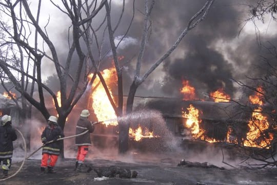 Feuerwehrleute versuchen den Brand des umgestürzten Tanklasters zu löschen.