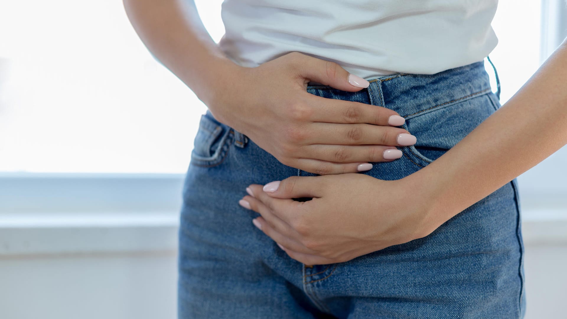 Eine Frau hält sich die Hände an den Unterbauch: Schmerzen treten in der Regel erst auf, wenn eines oder mehrere der Myome eine gewisse Größe erreicht haben.